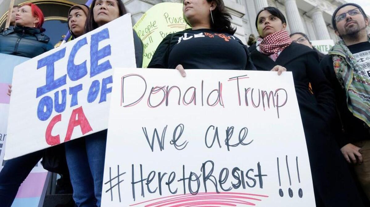 In this Jan. 25, 2017 file photo protesters hold signs as they listen to speakers at a rally outside of City Hall in San Francisco, Calif. Hundreds of bills await action by California lawmakers as the Legislature begins the last week of business this year. Among the issues is the so-called sanctuary state bill, which would restrict state and local aw enforcement agencies from cooperating with federal immigration authorities.