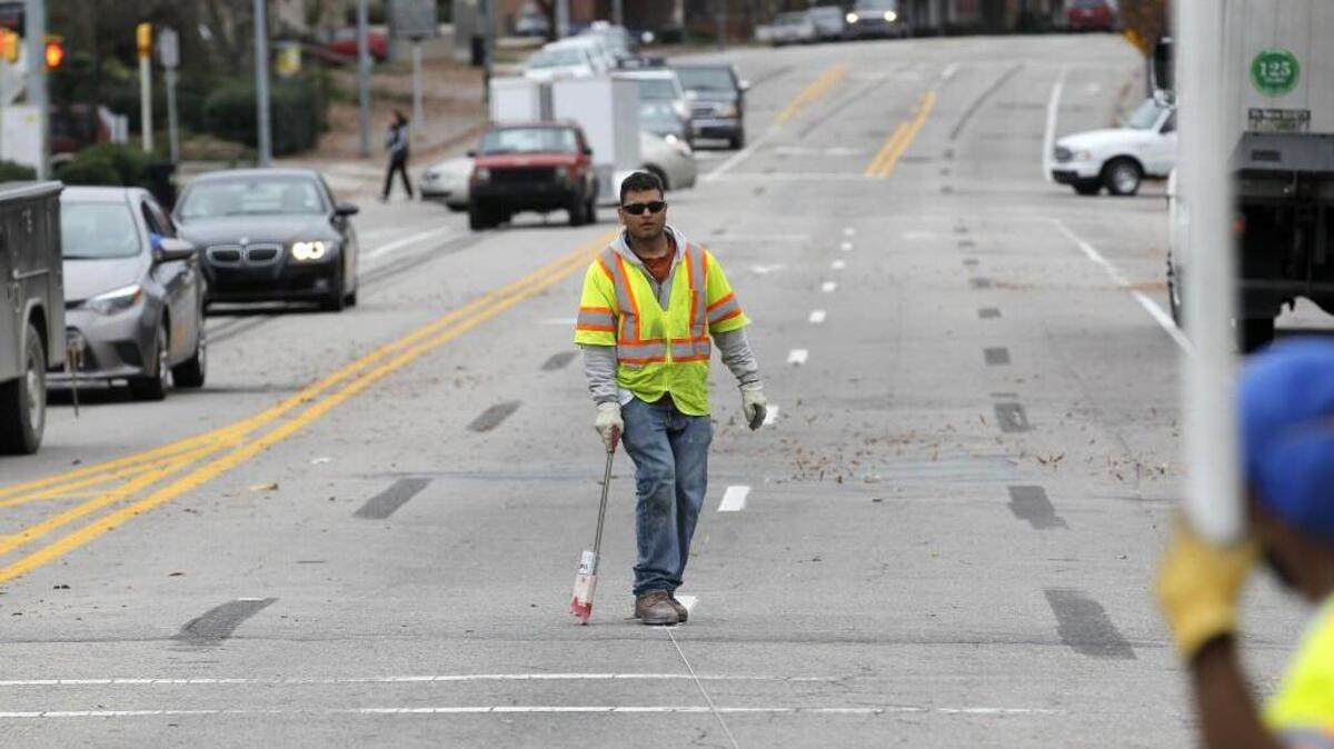 Felix Benitez with Clark Pavement Marking puts down guides for lane markers at the intersection of Hillsborough St. and Glenwood Ave. in Raleigh last December. Center lanes on many Raleigh streets have been moved as automobile lanes have been made fewer or narrower, all to make room for miles of new bike lanes. There is confusion and unhappiness from motorists about the changes.