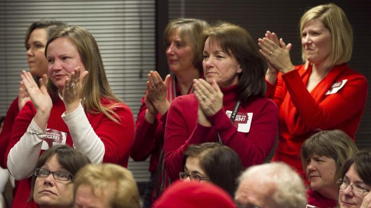 Some of the nearly 100 educators dressed in red, stand to show their support for Marcia Timmel, after she addressed the Wake County Board of Education asking them to oppose the state's elimination of teacher tenure in March, 2014 at the Wake County Board of Education in Cary, N.C.