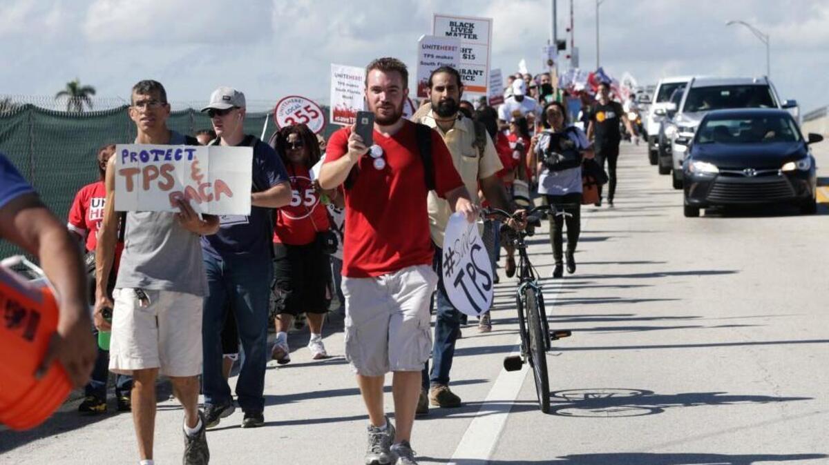 Protesters march to President Donald Trump's Mar-a-Lago resort, where he will be spending the Thanksgiving holiday, Tuesday, Nov. 21, 2017, in West Palm Beach, Fla. They were protesting the Trump administration's decision to end a temporary residency permit that has allowed almost 60,000 citizens from Haiti to live and work in the United States since an earthquake shook the Caribbean nation in 2010.