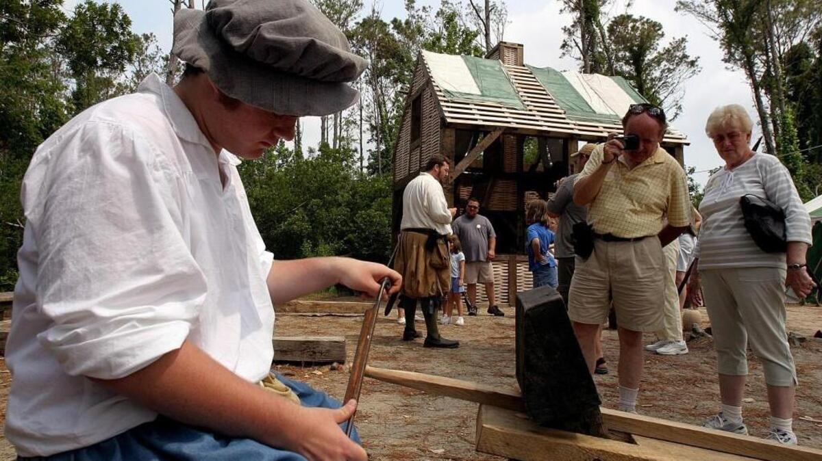 
 Ann Tyminkski and her husband Chester Tyminkski of Owings Mills, Md., take pictures of Sean Andrews who plays Jon Costigon as he works with a tool called a shavehorse, which was used to make parts for building in the Settlement Site at the Roanoke Island Festival Park in Manteo, N.C. Saturday June 5, 2004. 
