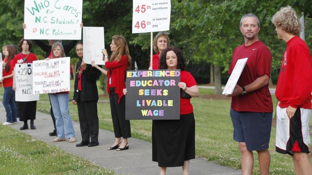Teachers, including Kristin VanBuskirk, center, a math teacher at Apex High School, rally against high turnover and low pay on the sidewalk in front of the school in May 2014.