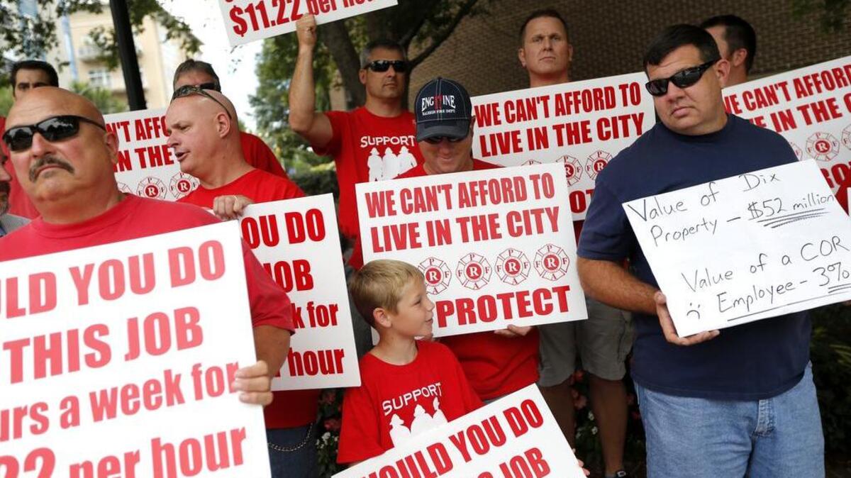 Raleigh firefighters and supporters, including, Raleigh firefighter Jake Corker, center, and his son, Gavin, 7, and Richard Ketchie, right, protest at the corner of West Hargett and S. Dawson Streets in downtown Raleigh before the Raleigh City Council meeting Tuesday, June 21, 2016. The firefighters were protesting the city's budget that did not give them a significant pay raise.