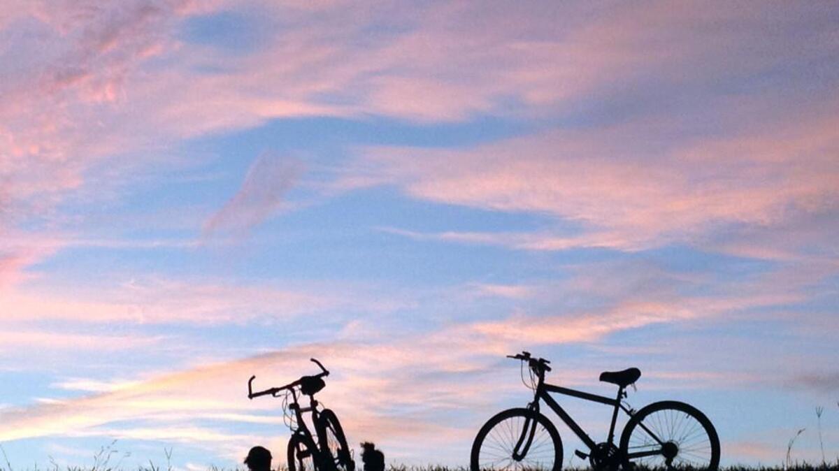 A pair of cyclists stop on the dam at Lake Raleigh to enjoy the sunset along the Walnut Creek Trail of the Raleigh Greenway system at N.C. State’s Centennial Campus.