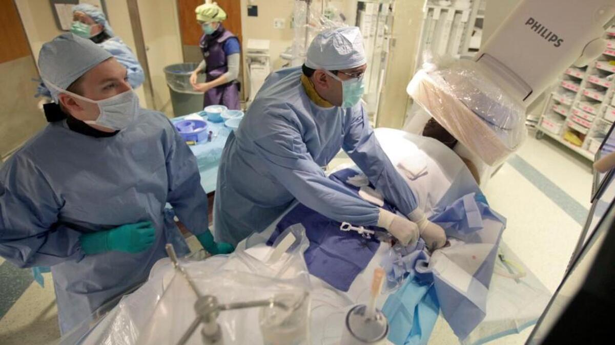 Dr. Manesh Patel, right, does a catheterization Wednesday on a patient’s arteries. Patel is part of a team that found the test may be overused.