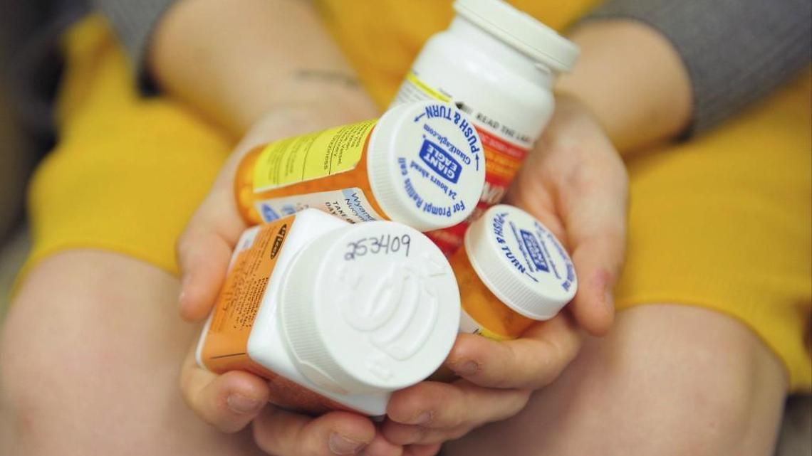 Heidi Wyandt, 27, holds a handful of her medication bottles at the Altoona Center for Clinical Research in Altoona, Pa., where she is helping test an experimental non-opioid pain medication for chronic back pain. With about 2 million Americans hooked on opioid painkillers, researchers are searching for less addictive drugs to treat pain.