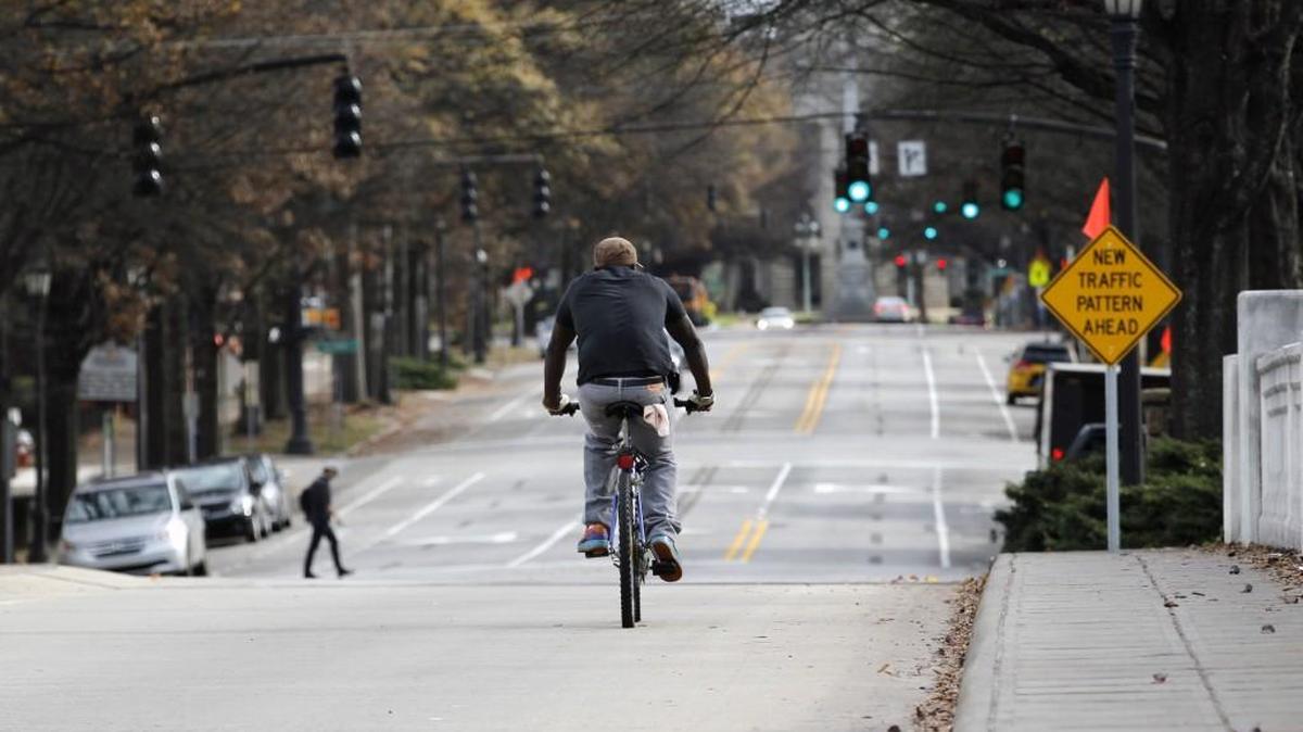A sign, right, warns of changed traffic patterns as a bicyclist rides over the railroad bridge on Hillsborough Street near Glenwood Avenue in Raleigh. Center lanes on many Raleigh streets have been moved to left here, to the right there, as can be seen in the background. Automobile lanes have been made fewer or narrower. All to make room for miles and miles of new bike lanes.
