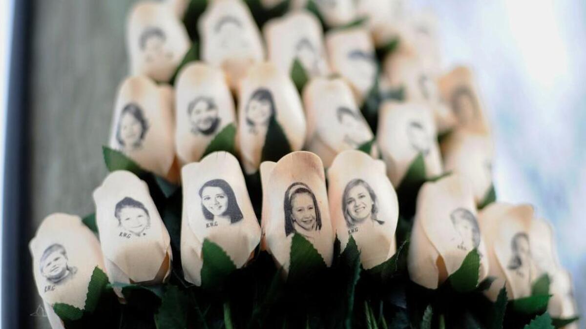 In this Jan. 14, 2013, file photo, white roses with the faces of victims of the Sandy Hook Elementary School shooting are attached to a telephone pole near the school in Newtown, Conn.