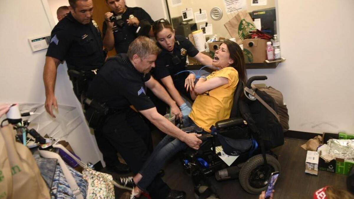 Dawn Russell gets arrested by Denver police officers after refusing to vacate the offices of Republican Sen. Cory Gardner in downtown Denver, Colo., Thursday, June 29, 2017. Police arrested a group of disabled protesters on Thursday evening who had spent three days camped out in Gardner’s office, demanding that he pledge to oppose the GOP’s health care plan.