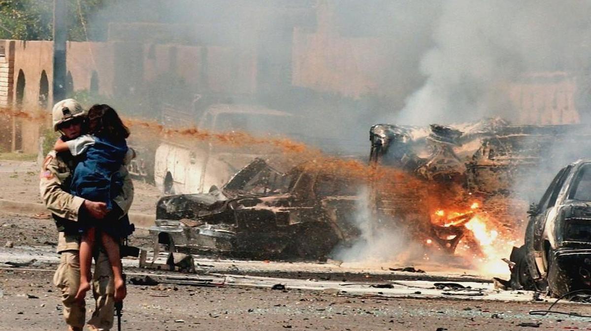A U.S. soldier carries an Iraqi girl away from the scene of three explosions in Baghdad, Iraq, in 2004.