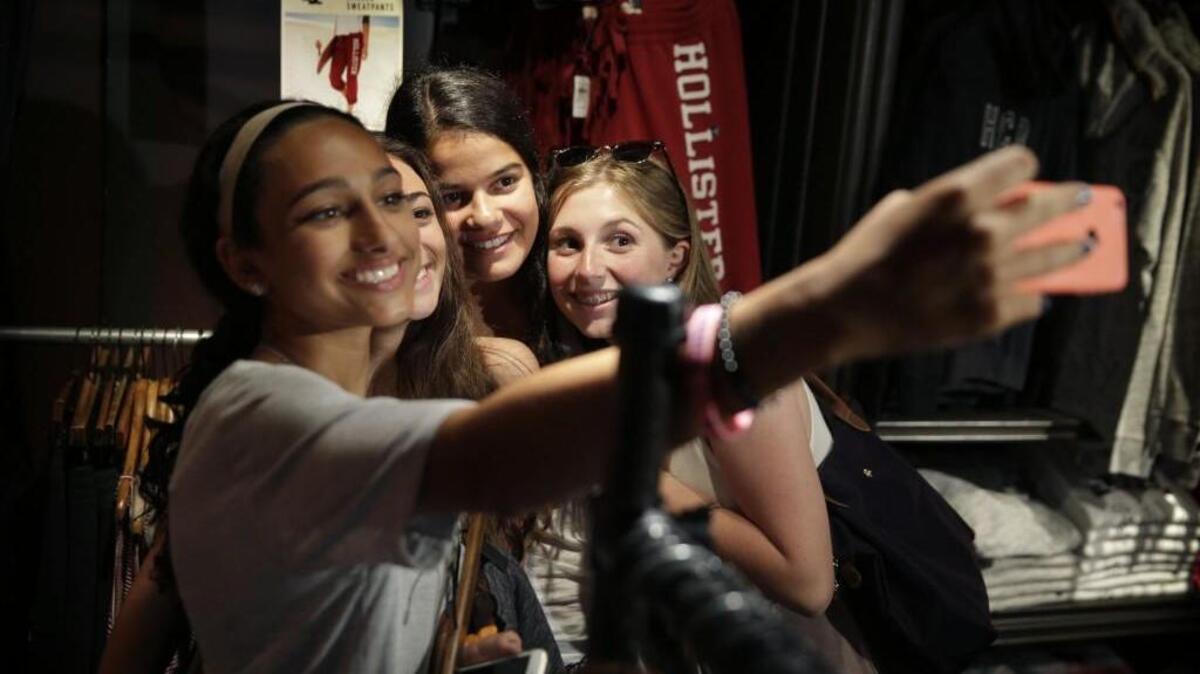 In this July 27, 2015, photo, Isabella Cimato, 17, left, Giulia Pugliese, 15, second from left, Arianna Schaden, 14, second from right, and Sofia Harrison, 15, try to get a good picture of themselves to demonstrate the use of social media at a shopping mall in Garden City, N.Y. Teens aren’t roaming around at the mall for kicks during back-to-school. They’re researching the looks they want online and follow popular hashtags on social media so they can piece together looks before they get there. (AP Photo/Seth Wenig)