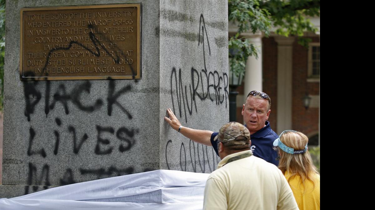 
Mike Coleman, general manager of CCI Environmental Services, touches the base of the Silent Sam statue on the UNC-CH campus as he evaluates the black spray paint damage.
