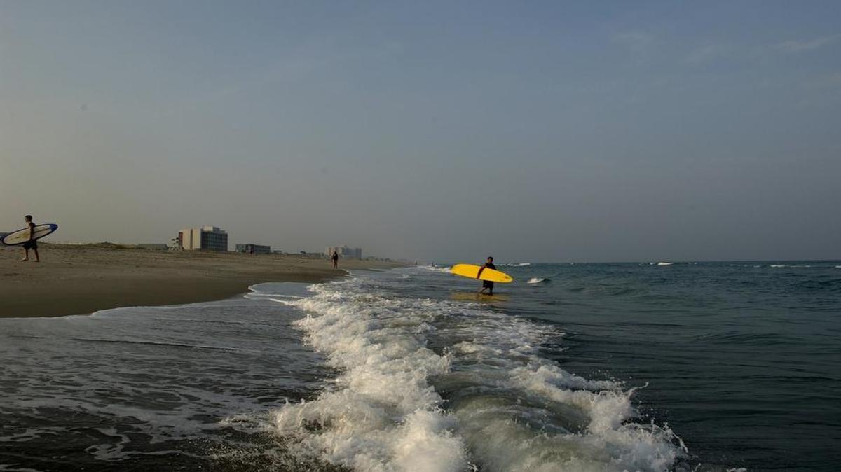 Surfers enjoy the waves along an empty shore on a late afternoon at Wrightsville Beach.