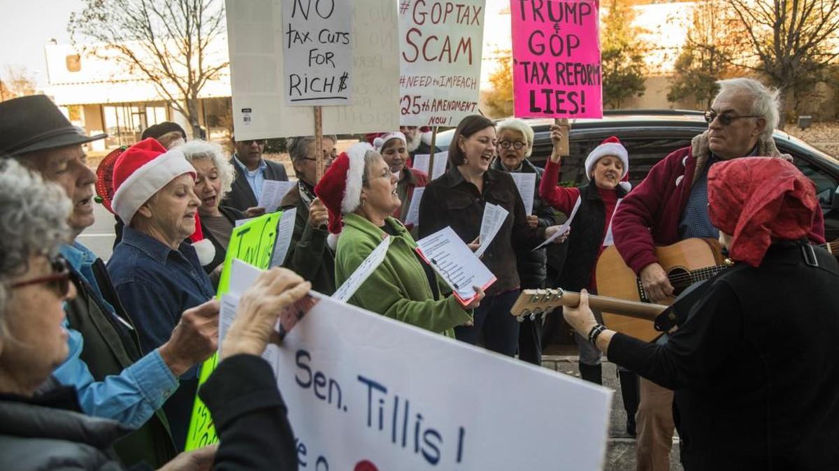A group of about 20 demonstrators sing anti-tax bill-themed Christmas carols outside the office of Sen. Thom Tillis at the federal courthouse building in Raleigh Thursday, Nov. 30, 2017. Protesters have been staging weekly demonstrations outside the office of Sen. Tillis since the inauguration of President Donald Trump.