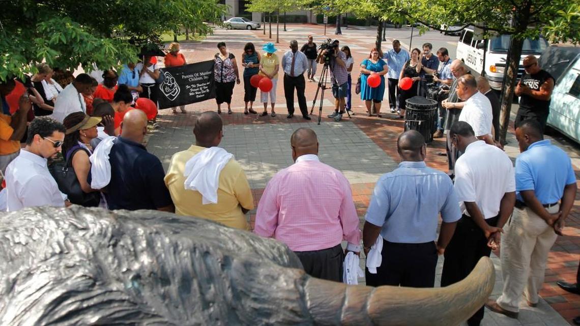 Under the gaze of the giant bronze bull at Foster and Corcoran Streets at CCB Plaza in downtown Durham, NC Monday afternoon, June 16, 2014, a group of about 30 joined hands in a 30 minute prayer vigil to pray for the victims of homicide and peace for Durham. The Religious Coalition for A Nonviolent Durham and the Parents of Murdered Children, Inc. joined a group of NC funeral directors promoting the national Stop the Violence Now campaign at the plaza Monday.
