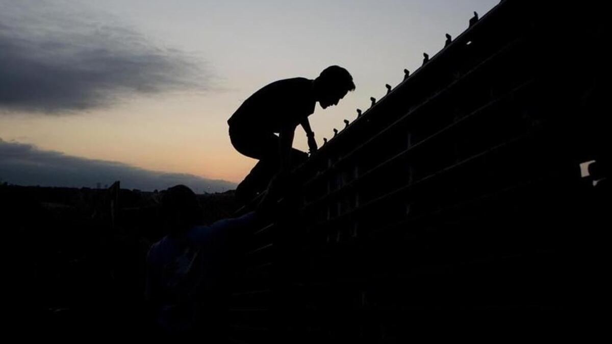 A man climbs the border wall to cross into the United States from Tijuana, Mexico, on Sept. 11, 2008.