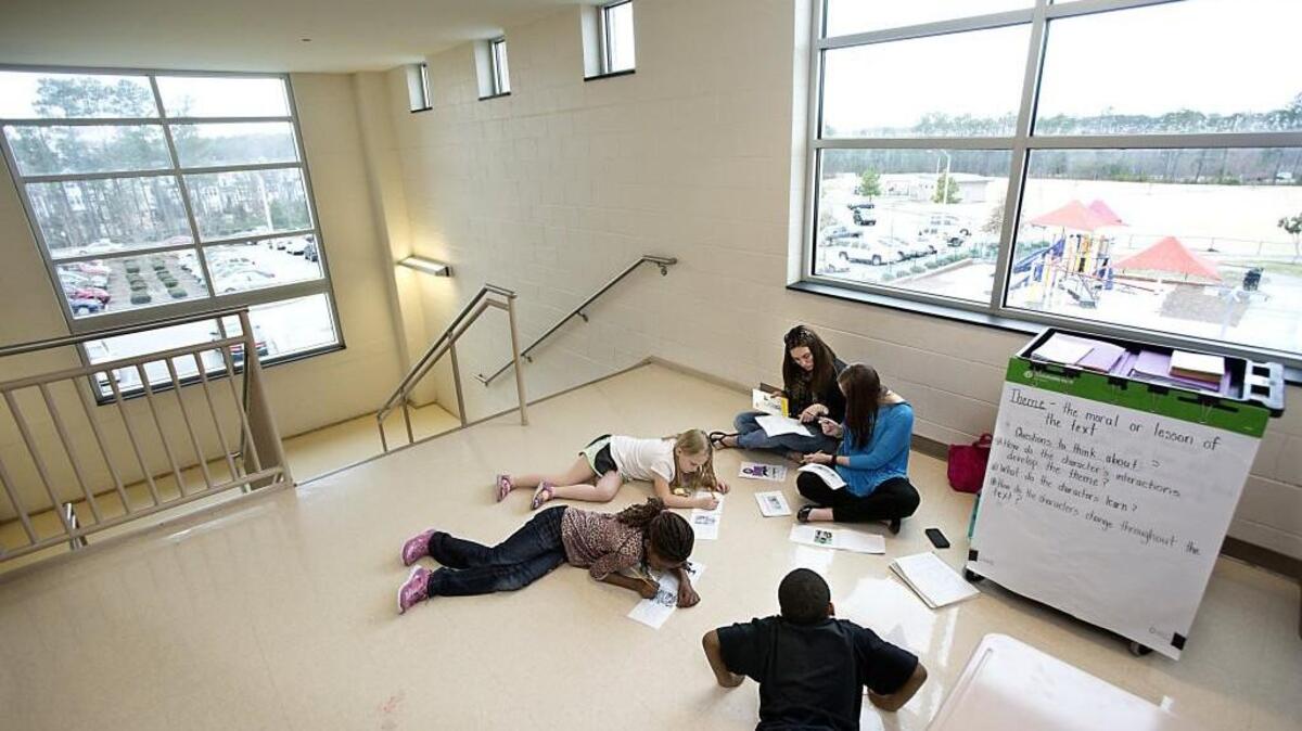 Holding class in a stairwell area at Brier Creek Elementary School, teachers confer about a reading assessment for one of their students on Wednesday, March 11, 2015.