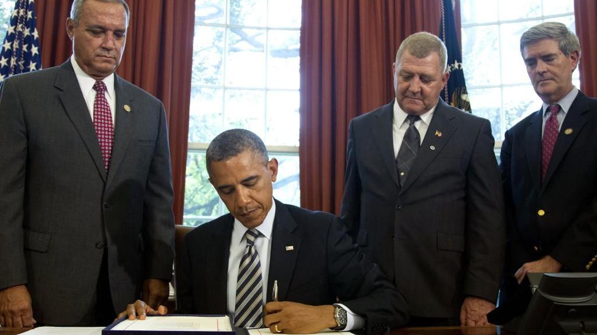 President Barack Obama signs the Honoring America's Veterans and Caring for Camp Lejeune Families Act of 2012 on Monday, Aug. 6, 2012, in the Oval Office at the White House in Washington. From left are, Rep. Jeff Miller, R-Fla., Jerry Ensminger, former Master Sergeant, USMC, who served at Camp Lejeune and advocated on behalf of affected veterans and families, and Rep. Brad Miller, D-N.C. Ensminger blames contaminated water at Camp Lejeune for the leukemia that killed his 9-year-old daughter.