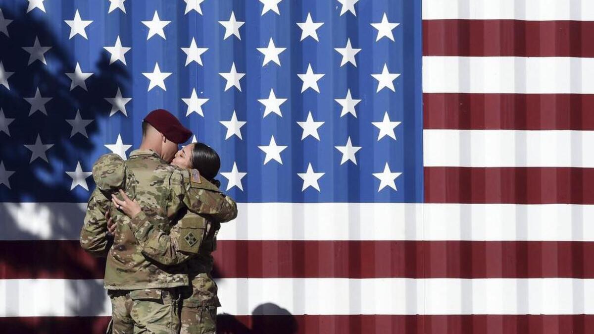 Sgt. Patrician Nunez, right, gives a kiss to her husband, Spec. Adrian Ramos, while their family took photos after a Ft. Carson homecoming after nine months in Afghanistan, in Colorado Springs, Colo., on Monday. Nunez was one of about 95 Ft. Carson soldiers made it home in time for Thanksgiving