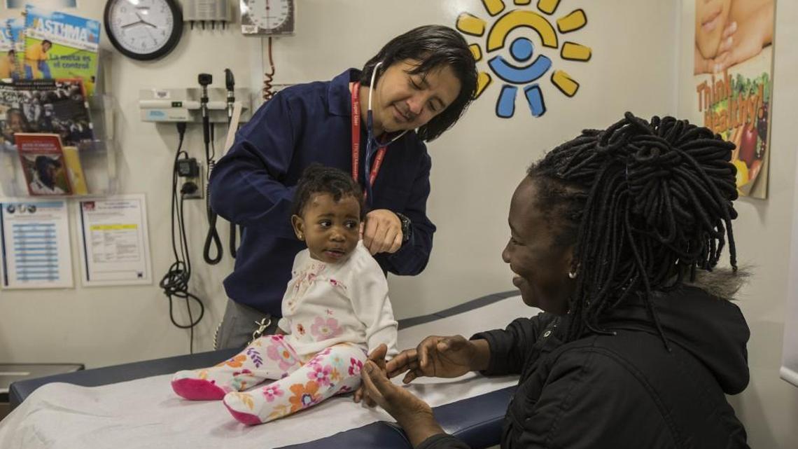 A mother sits with her 9-month-old daughter as Dr. Scott Ikeda gives her a checkup at the New York Children's Health Project mobile medical clinic in New York, Nov. 15, 2016. Pediatricians express concerns about the impact the American Health Care Act will have on children.