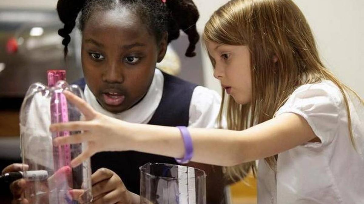 Third-grader Autumn Lynch, left, and second-grader Riley Dunnam measure their ecosystem soda bottle before cutting it in half in biotech science teacher Valerie Chambers’ science class at Durham’s Reaching All Minds Academy charter school.