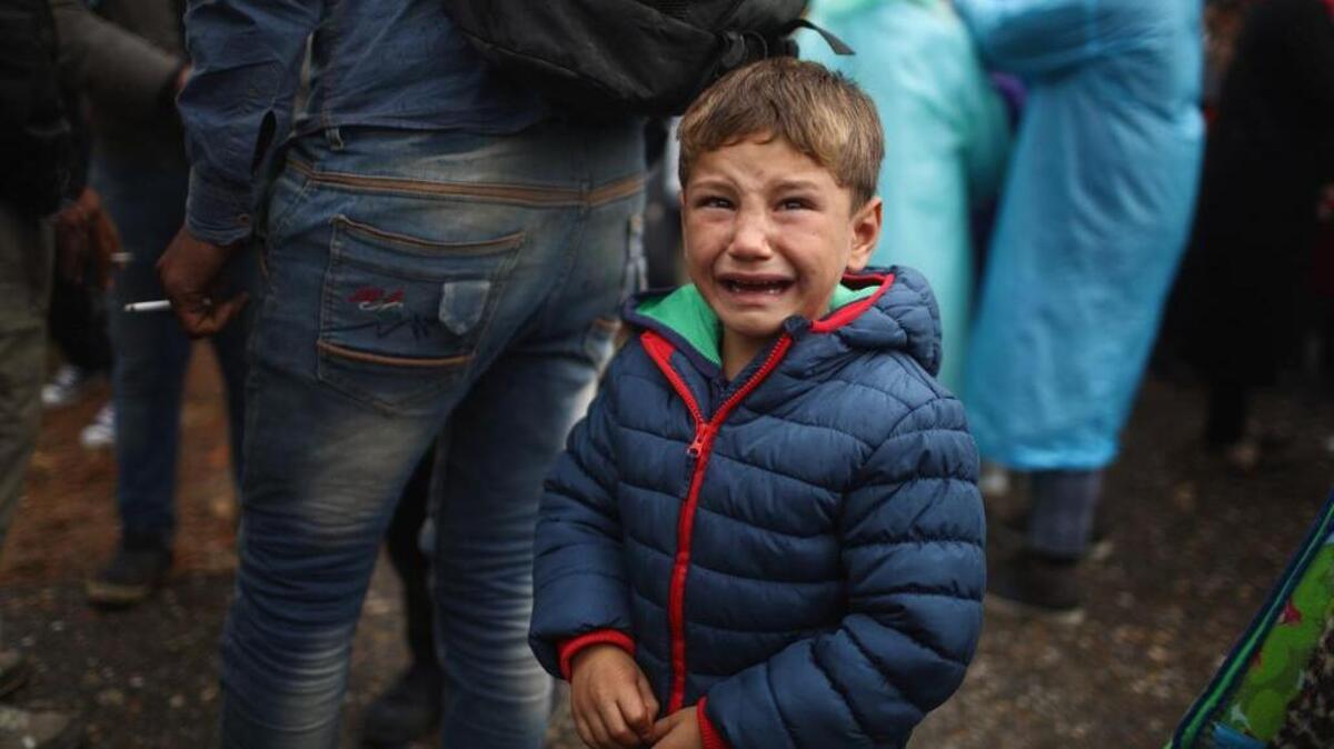A migrant boy suffers in the cold and rain as he and his family make their way through Serbia toward Hungary.