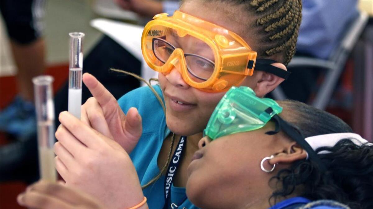 From left, middle school students Jalen Bynum and Jerlia Edmunds compare notes and watch each other’s DNA extraction results as they watch small strands of fruit DNA rise to the top of their test tubes during a DNA extraction exercise Aug. 1, 2015 at the Friday Institute for Educational Innovation.