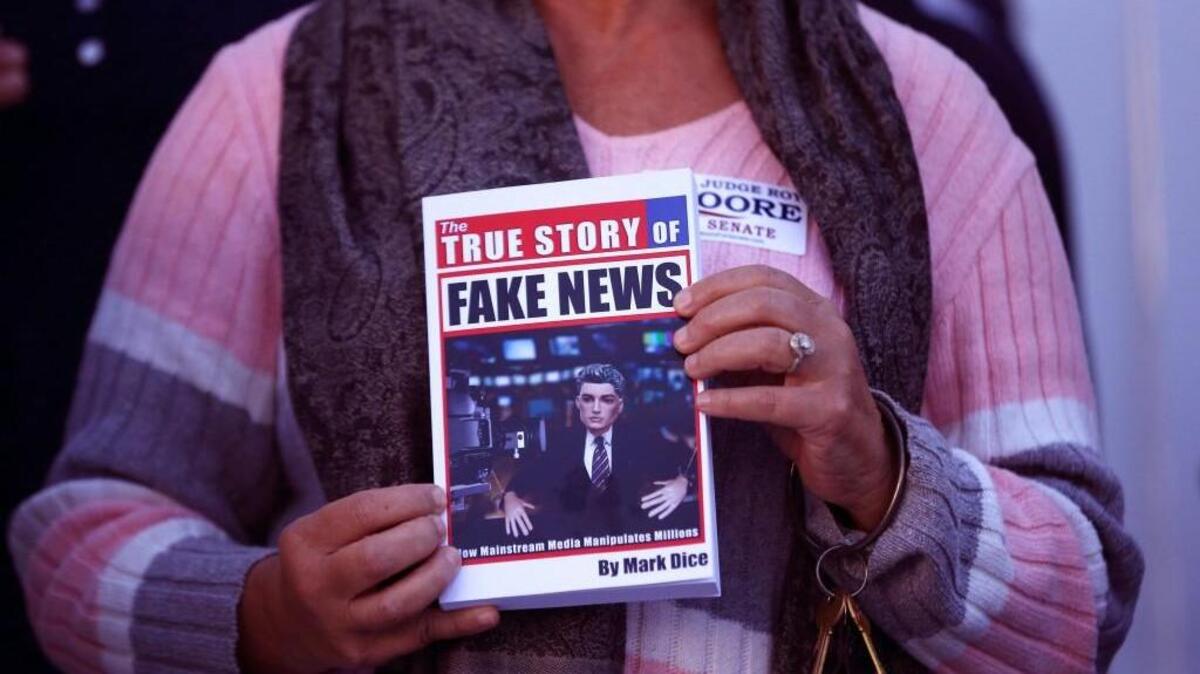 In a Nov. 17, 2017 file photo, a supporter holds up a "Fake News" book while Kayla Moore, wife of U.S. Senate candidate Roy Moore, speaks at a press conference in Montgomery, Ala.