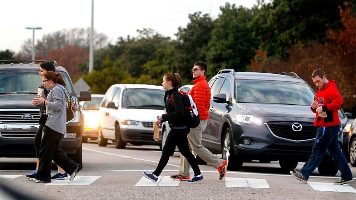 Pedestrians cross a wide and busy Western Boulevard at Avent Ferry Road near N.C. State University's campus.