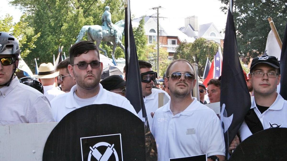 In this Saturday, Aug. 2017 photo, James Alex Fields Jr., second from left, holds a black shield in Charlottesville, Va., where a white supremacist rally took place. Fields was later charged with second-degree murder and other counts after authorities say he plowed a car into a crowd of people protesting the white nationalist rally.