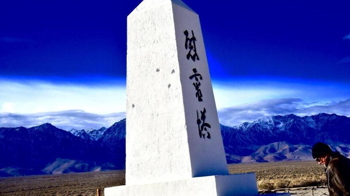 Dave Daniel, a Boston area writer, bows his head at the cemetery monument at Manzanar.
