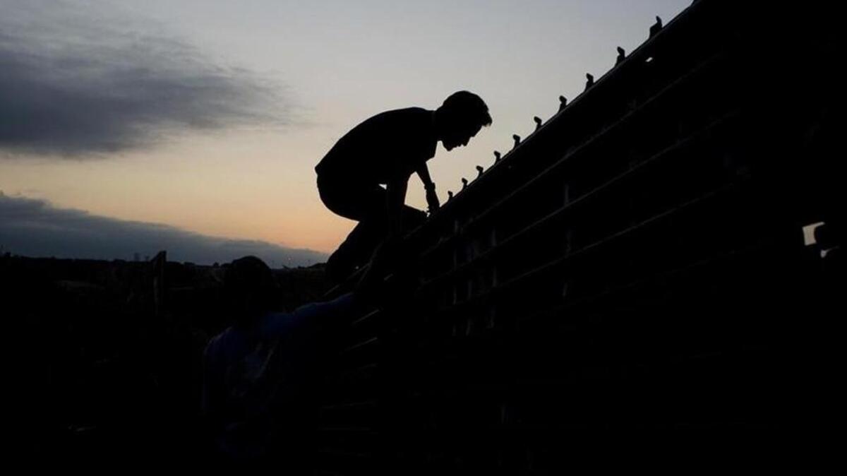 A lone figure climbs a wall on the US-Mexican boarder.