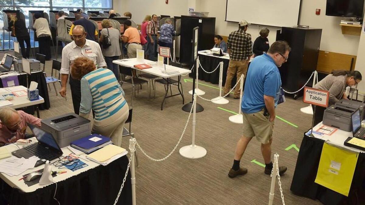 Early voting site officials (left) work on processing special ballots while a steady stream of voters files through the polling place even in the late morning at the Wake County Eastern Regional Center in Zebulon on Oct. 21.