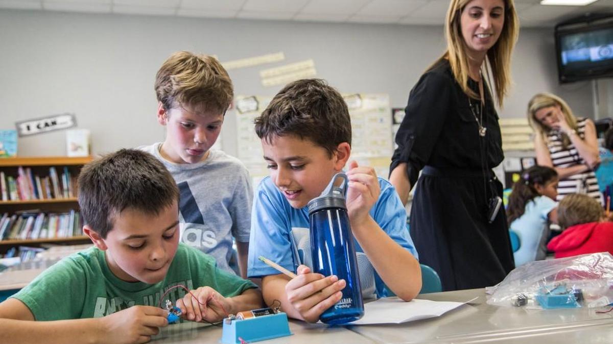 Fourth-grader teacher Katy Trainor, right, watches as, from left, Lucas Bedont, Ryan Olson and Matthew LaRusso take part in a lesson on electrical circuits in April at Salem Elementary School in Apex.