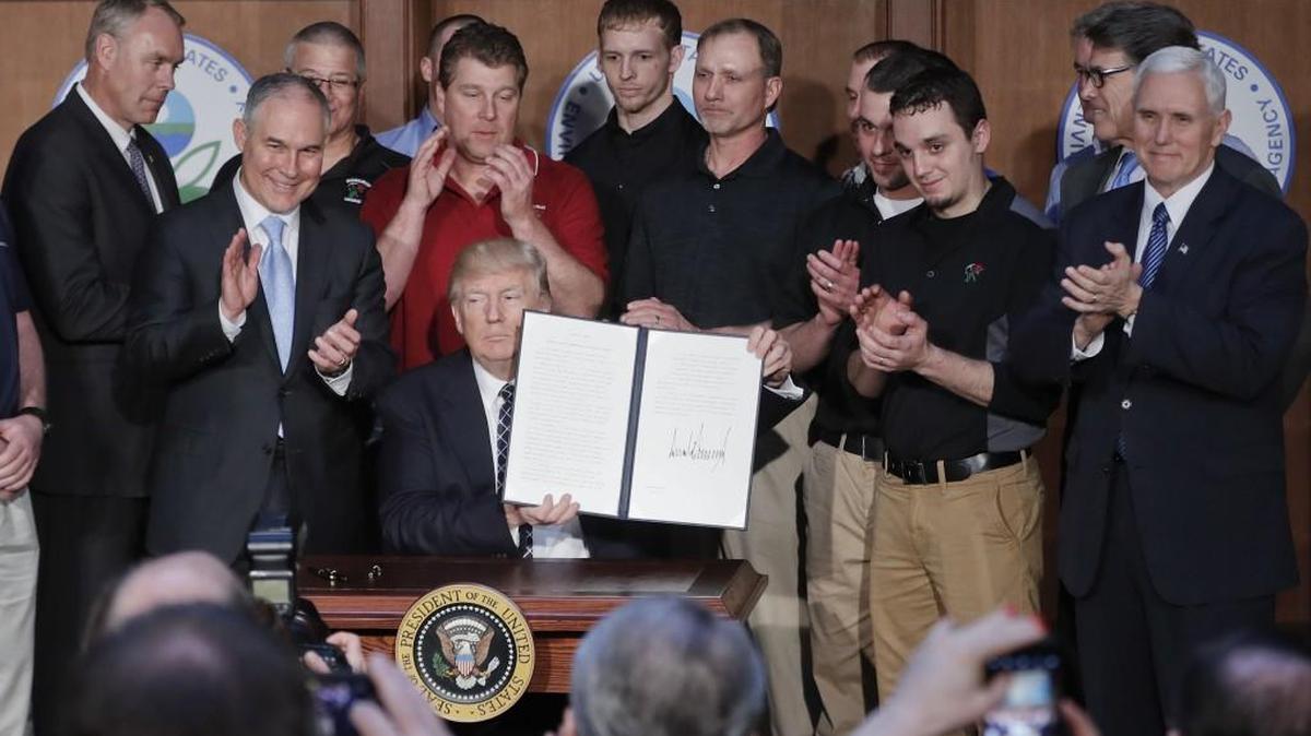 President Donald Trump, accompanied by coal miners and EPA Administrator Scott Pruitt, second from left, holds up the signed Energy Independence Executive Order.