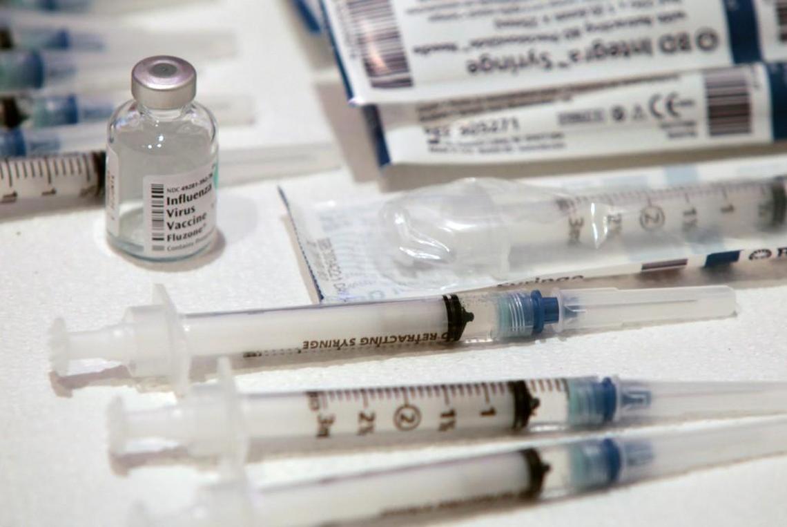 A bottle of Influenza Virus Vaccine, left, and stacks of syringes await a line of Murdoch Center employees in the Chapel of the Murdoch Center, Butner, NC Wednesday afternoon, Oct. 9, 2013.