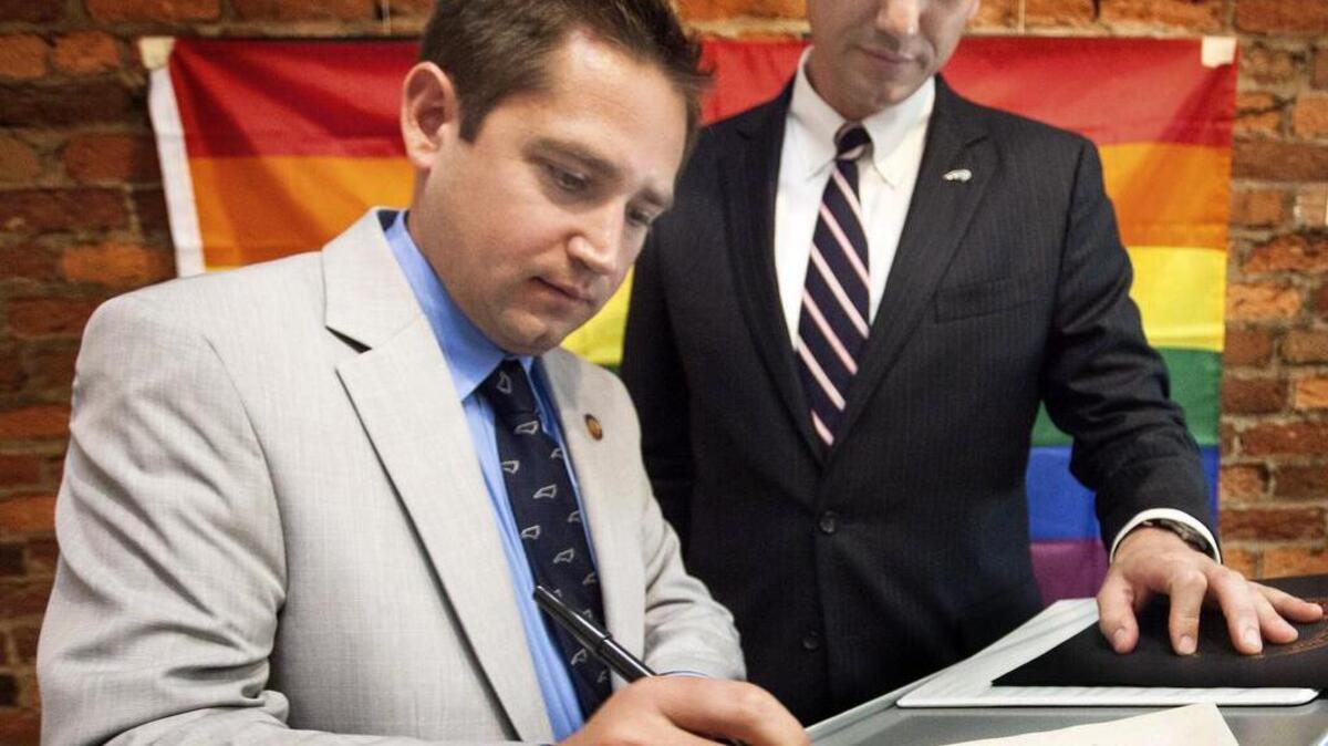 Chris Sgro, left, signs the Oath for Members of the House of Representatives as Rep. Brian Turner of Buncombe County watches following a swearing-in ceremony for Sgro at the LGBT Center of Raleigh. Sgro was appointed to the House in April after Rep. Ralph Johnson of Greensboro died.