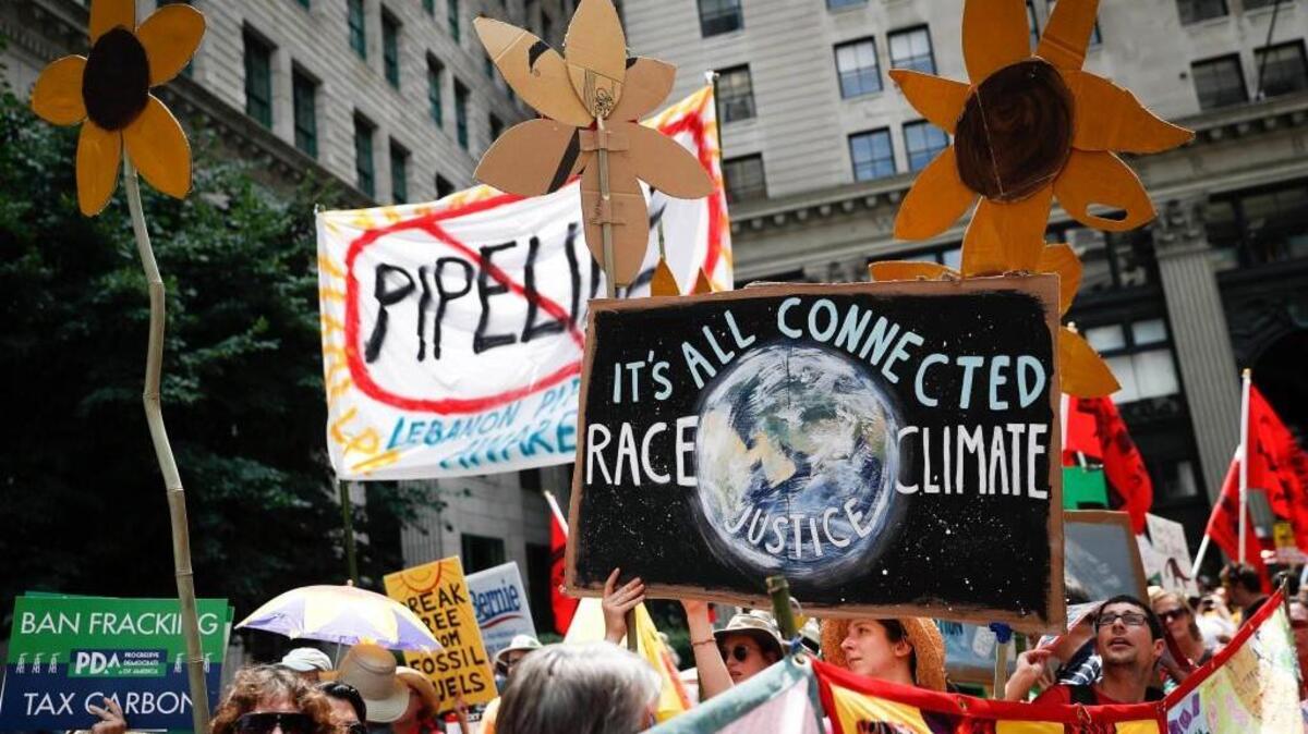 In this Sunday, July 24, 2016 file photo, climate change activists carry signs as they march during a protest in downtown in Philadelphia a day before the start of the Democratic National Convention.