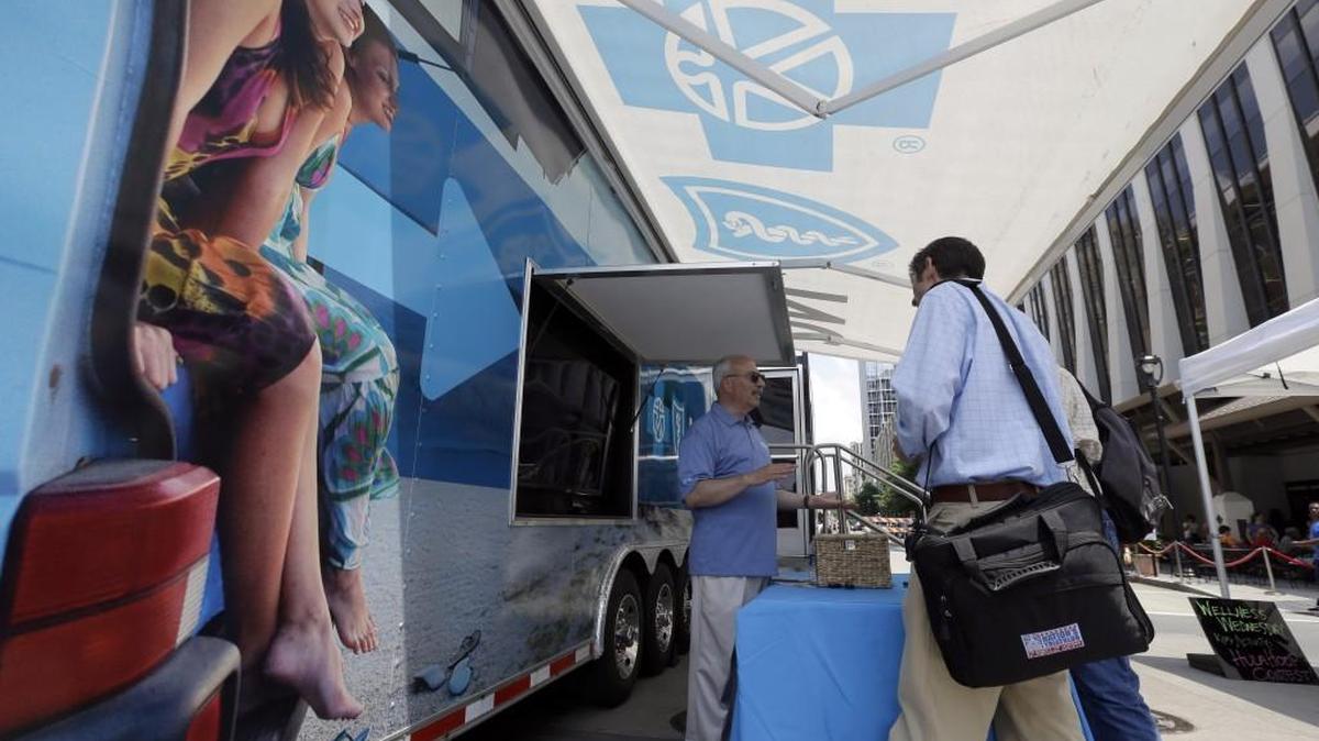 Blue Cross Blue Shield of North Carolina employee Lew Borman, left, helps a customer outside a trailer at the downtown farmer’s market in Raleigh.