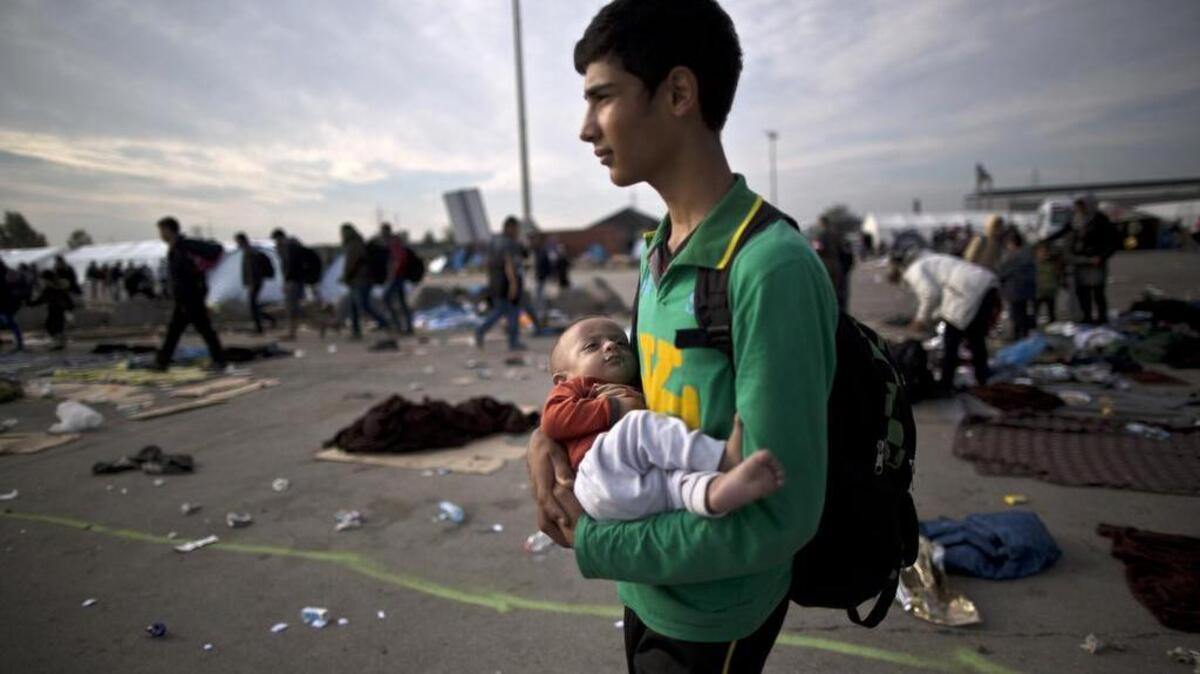 
Afghan refugee Rasoul Nazari, 15, holds his 10-month-old nephew Imran after crossing the border between Hungary and Austria in Nickelsdorf, Austria. 
