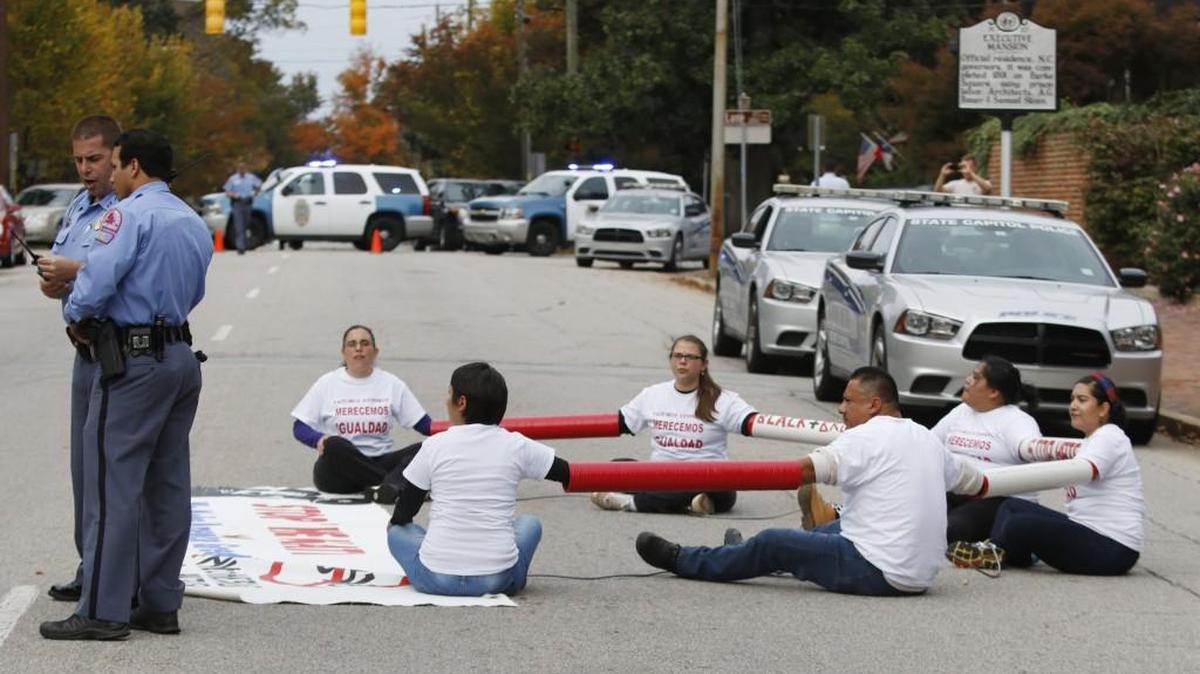 Raleigh police officers confer while six immigration protestrrs who shackled themselves together block North Blount Street in front of the Governor’s Mansion. The protesters were eventually cut apart and individually arrested and removed from the street. The immigration protesters were part of a larger very vocal crowd on the sidewalk protesting N.C. Gov. Pat McCrory’s signing of HB318 tightening immigration laws in NC.