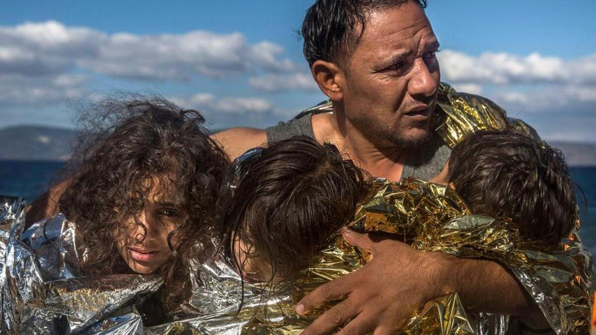 A man holds three children wearing thermal blankets after their crossing from Turkey to the Greek island of Lesbos. The Greek government says it is preparing a rent-assistance program to cope with a growing number of refugees, who face the oncoming winter and mounting resistance in Europe.