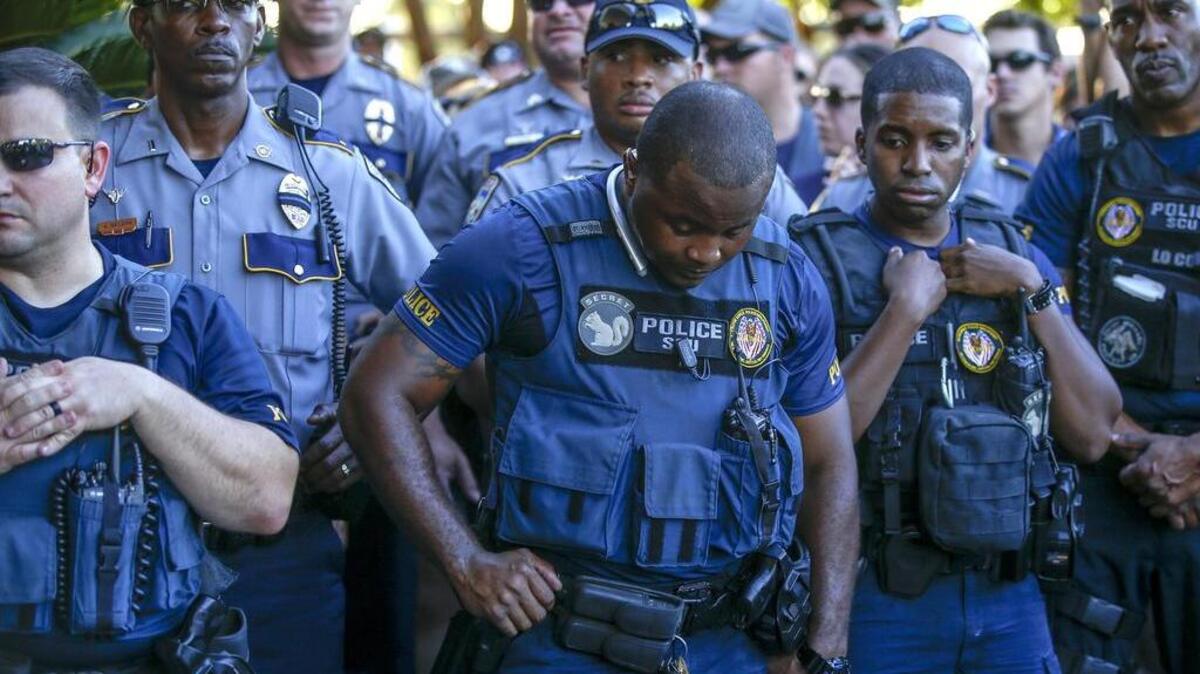 Baton Rouge police officers listen to speakers during a rally with nearly 400 motorcycle riders from various local clubs, who rode to police headquarters to show their support.