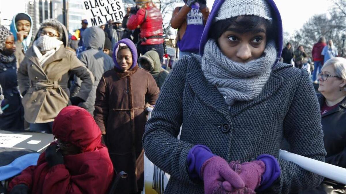Marcher Brianne Alston holds up her end of the Greensboro NAACP banner while listening to speakers in the freezing cold and wind in front of Memorial Auditorium in downtown Raleigh during the opening rally part of the 10th annual Historic Thousands on Jones Street protest march.