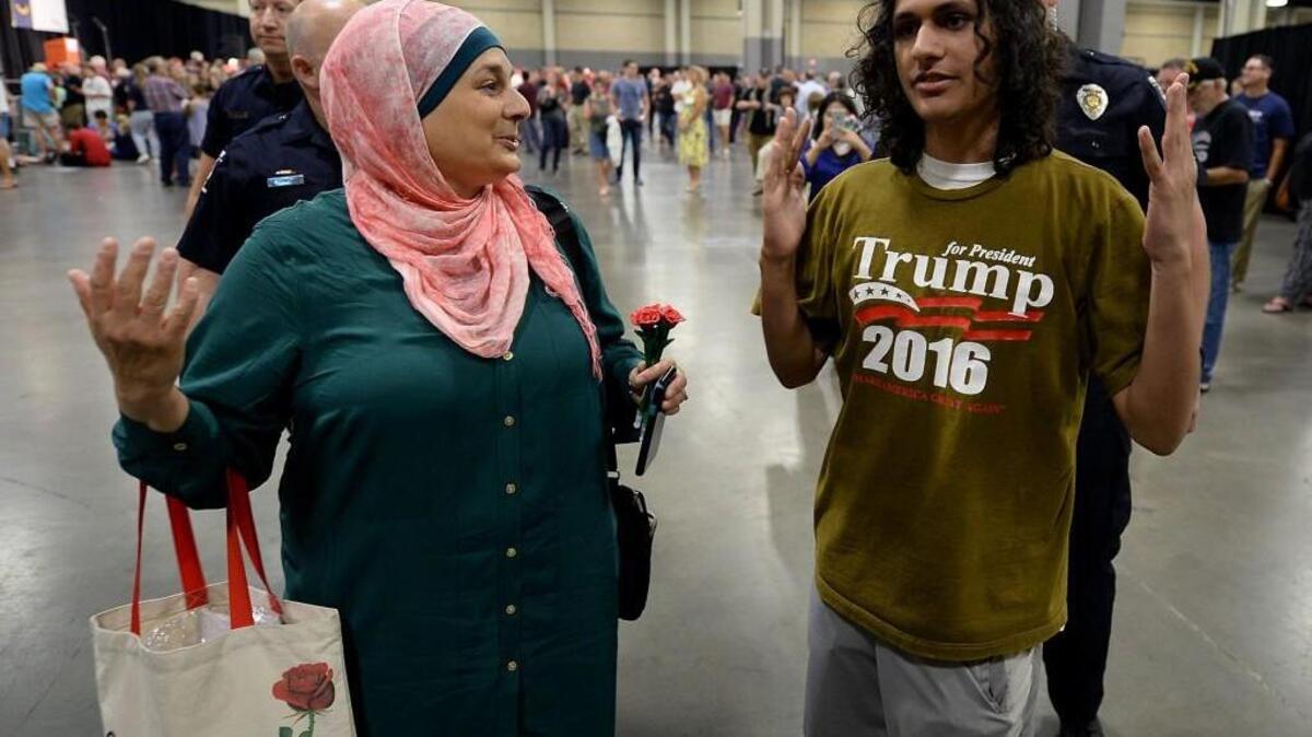Rose Hamid, left, and Jake Anantha, right, are escorted from the Charlotte Convention Center prior to a rally for GOP presidential candidate Donald Trump.