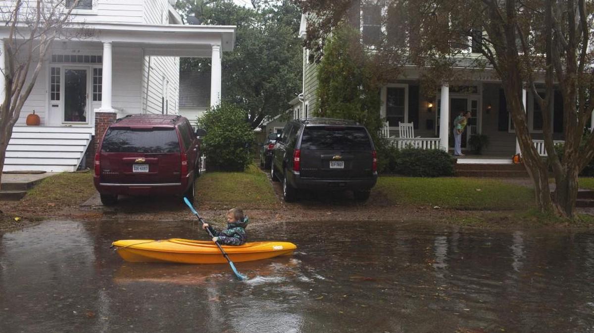 A boy kayaks in flood waters caused by Hurricane Sandy in Norfolk, Va., in 2012. Much of the population and economy of the country are concentrated on the East Coast, which accumulating scientific evidence suggests will be a global hot spot for a rising sea level over the coming century.