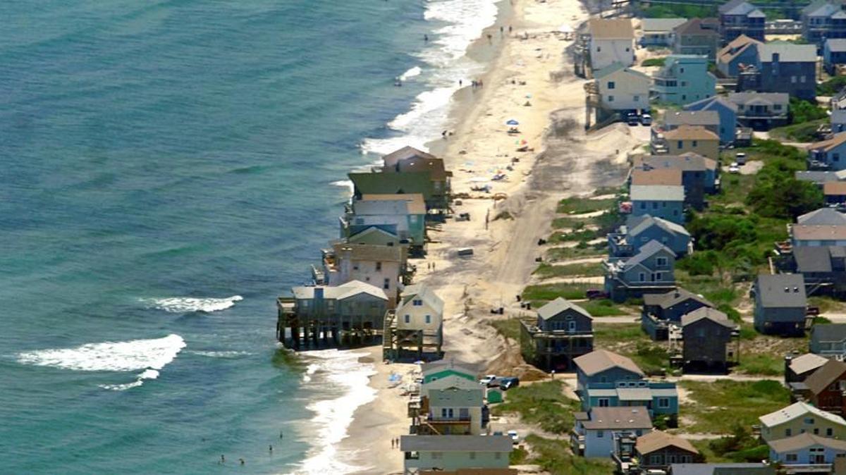 Waves crash under a row of beach houses in south Nags Head in 2010, which planned a $36 million project to pump fresh sand onto its eroding strand. Rising sea level will only magnify the damages of erosion and storms on the state's oceanfront and sounds, scientists say.
