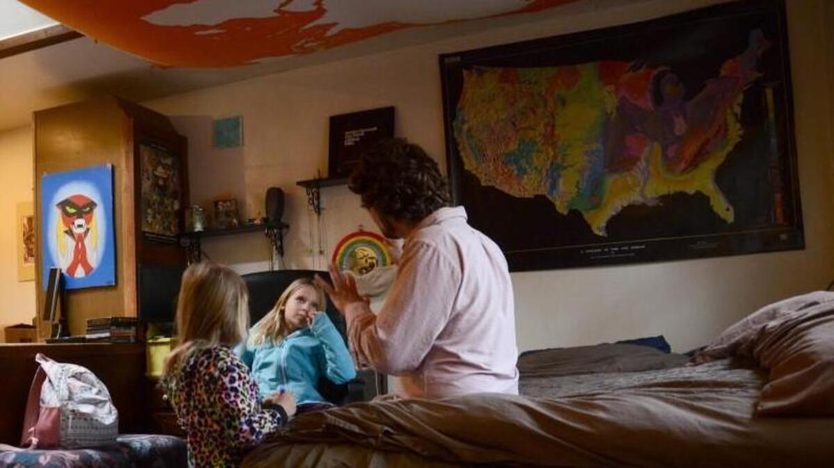 In this Tuesday, Nov. 28, 20017 photo, TC Bell sits with his two daughters before they get dressed for school, at their home in Denver. Bell's daughters are recipients of the Children's Health Insurance Program or CHIP, which is a program that provides low-cost coverage to families who earn too much to qualify for Medicaid. Arizona, California, Colorado, Minnesota, Ohio, Oregon and the District of Columbia are among the first expected to exhaust their CHIP allotments.
