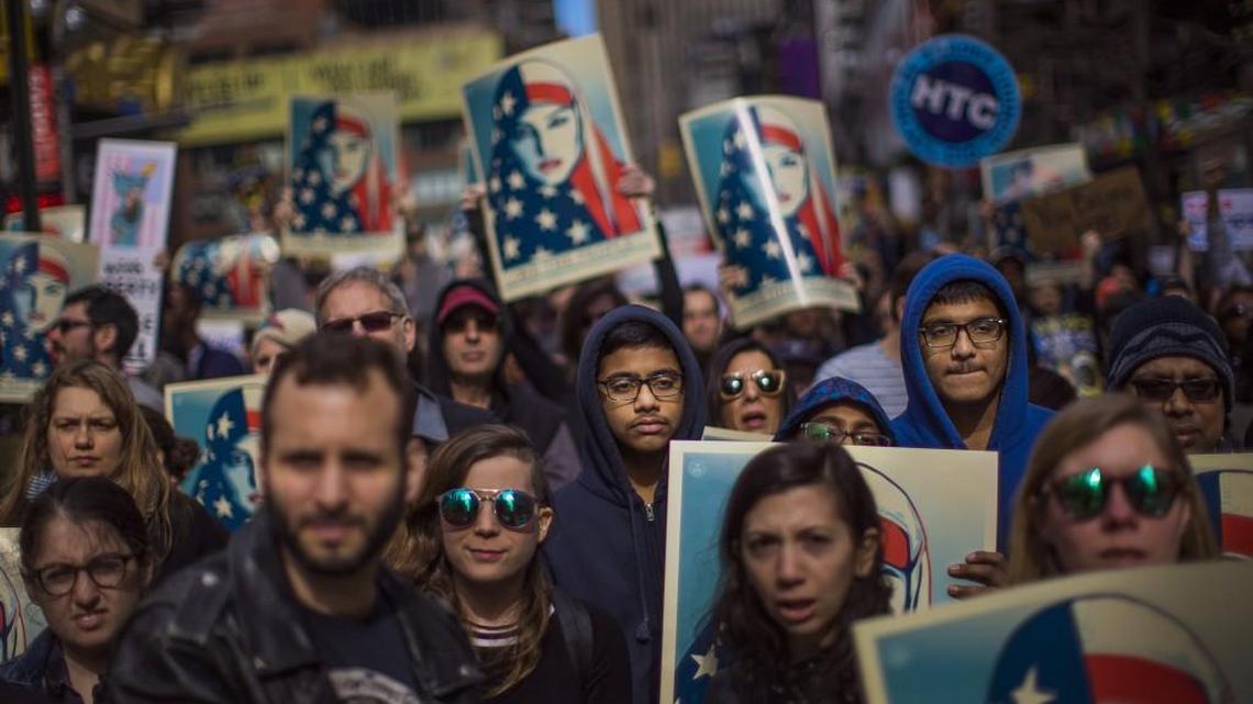 People carry posters during a rally in support of Muslim Americans and protest of President Donald Trump's immigration policies in Times Square, New York, Sunday, Feb. 19, 2017.