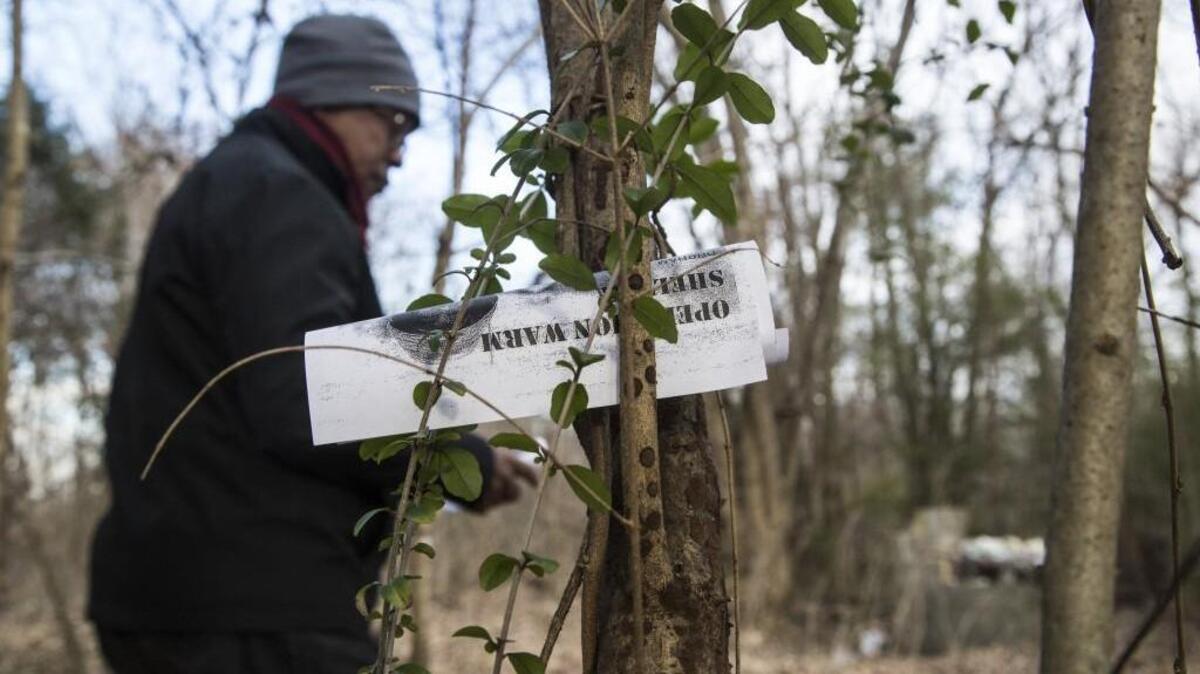 Chaplain Lynn Holloway leaves a flier at a homeless camp in Durham.